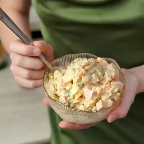 a woman holding a bowl of potato salad