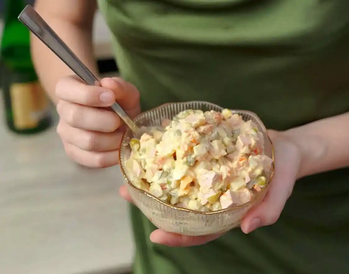 a woman holding a bowl of potato salad