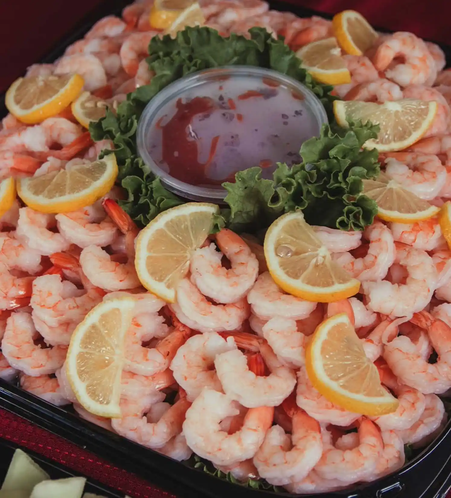 shrimp and lemons arranged around a cup of sauce and garnish